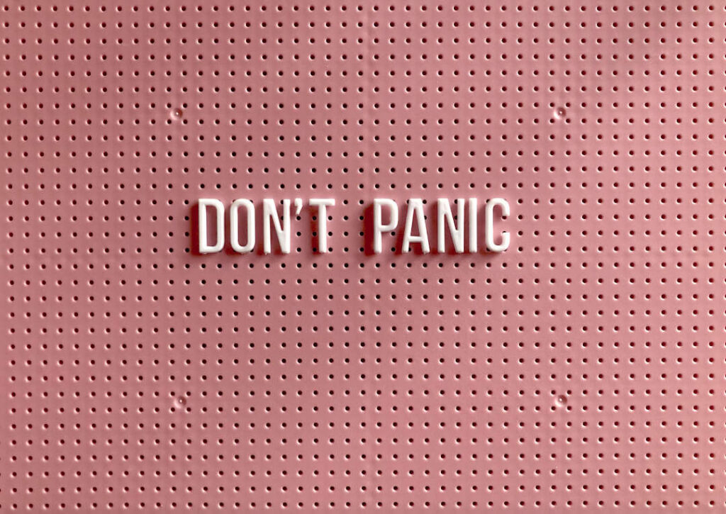 panic disorder and panic attacks – illustrated by a pink peg board sign with white letters that reads 'DON'T PANIC'