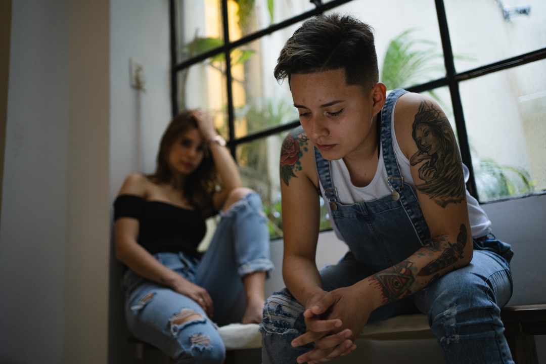 Lesbian couple looking upset after having an argument at home. LGBTQ Couples Therapy in Melbourne – Safe Place Therapy